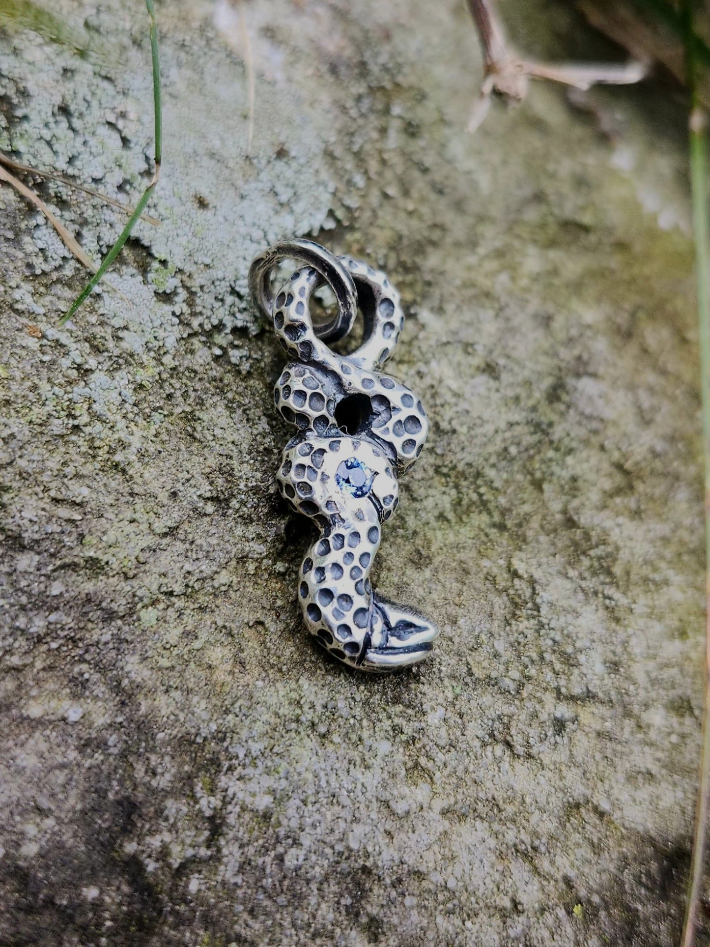Close-up of patinated silver serpent with blue sapphire center stone