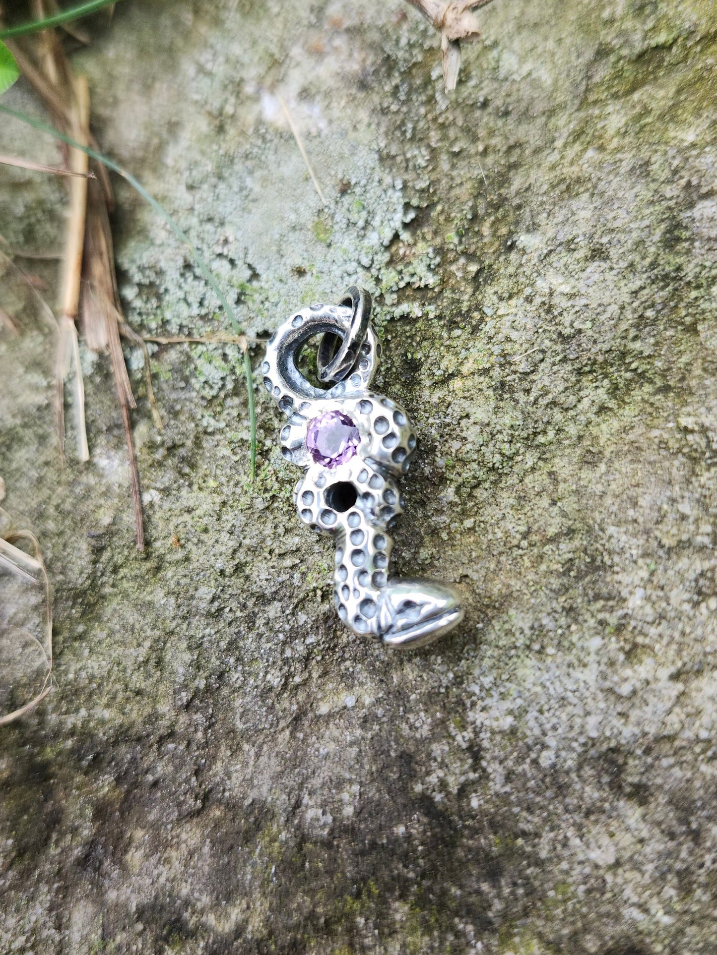 Amethyst snake pendant on mossy stone background, artisan jewelry