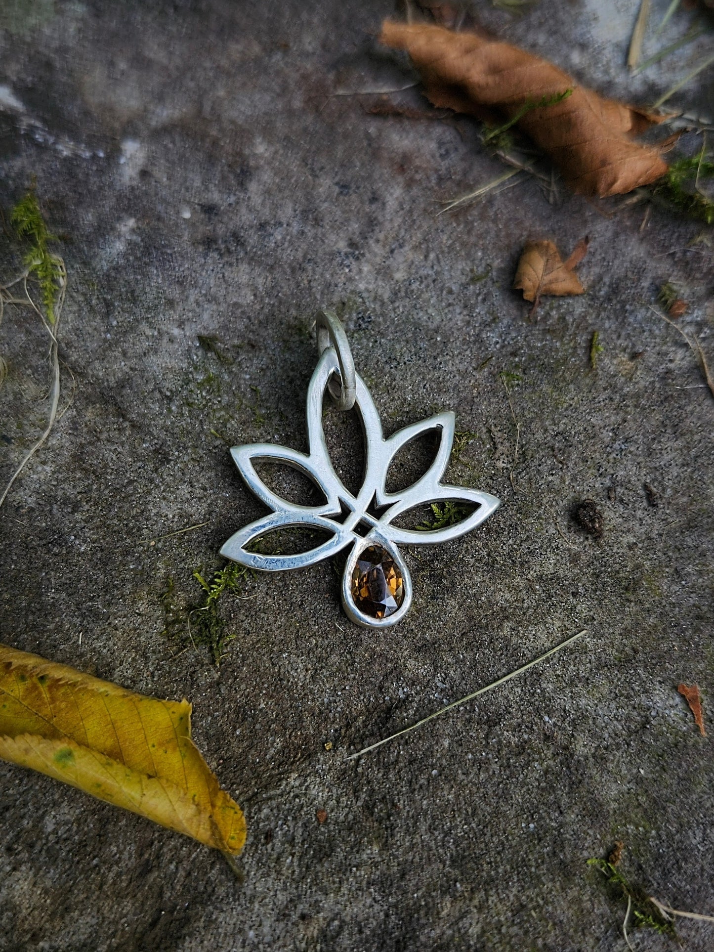 Silver pendant with a gemstone on a textured stone surface