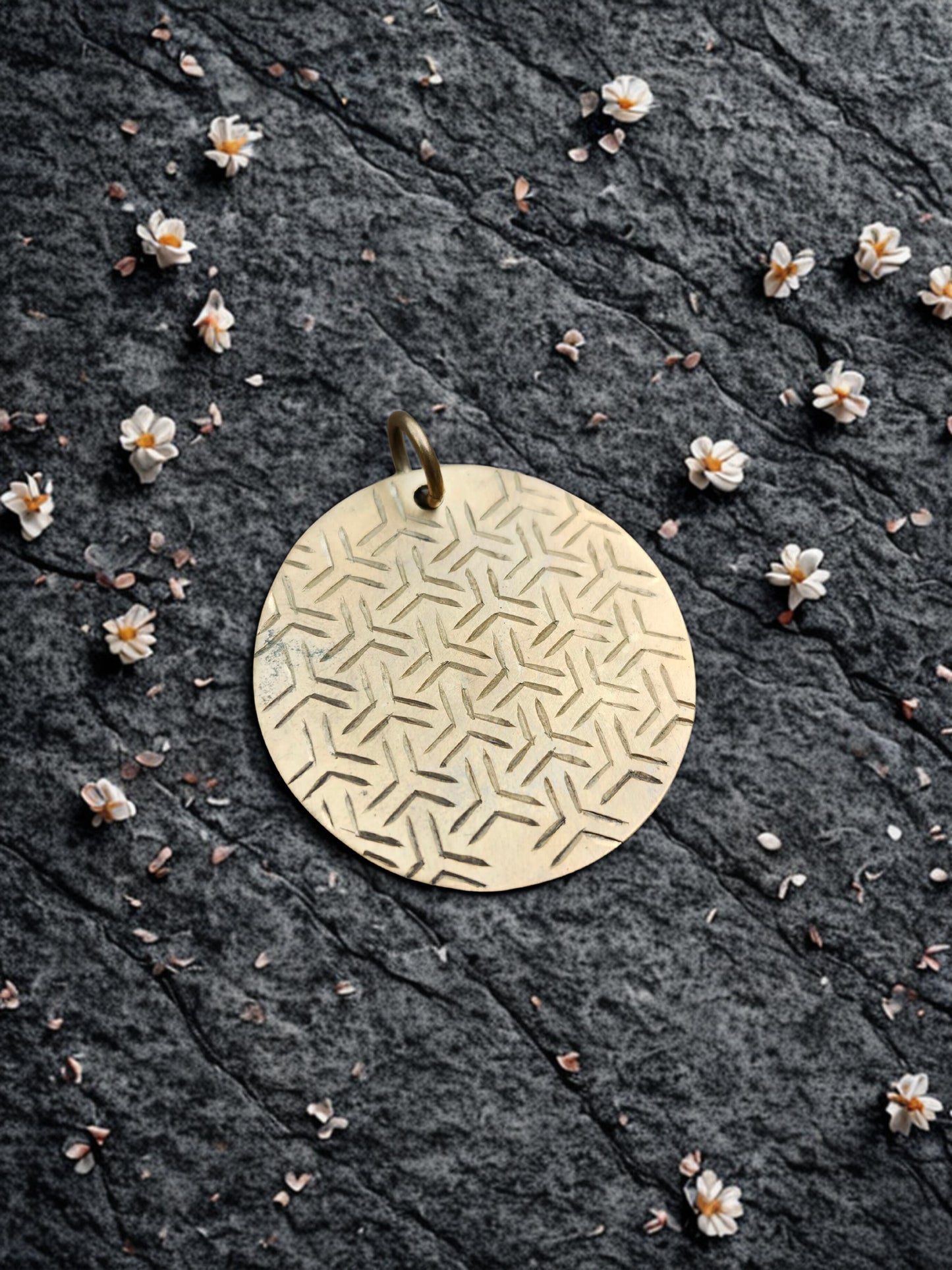Reverse side of pendant with traditional geometric pattern, held in gloved hand.
