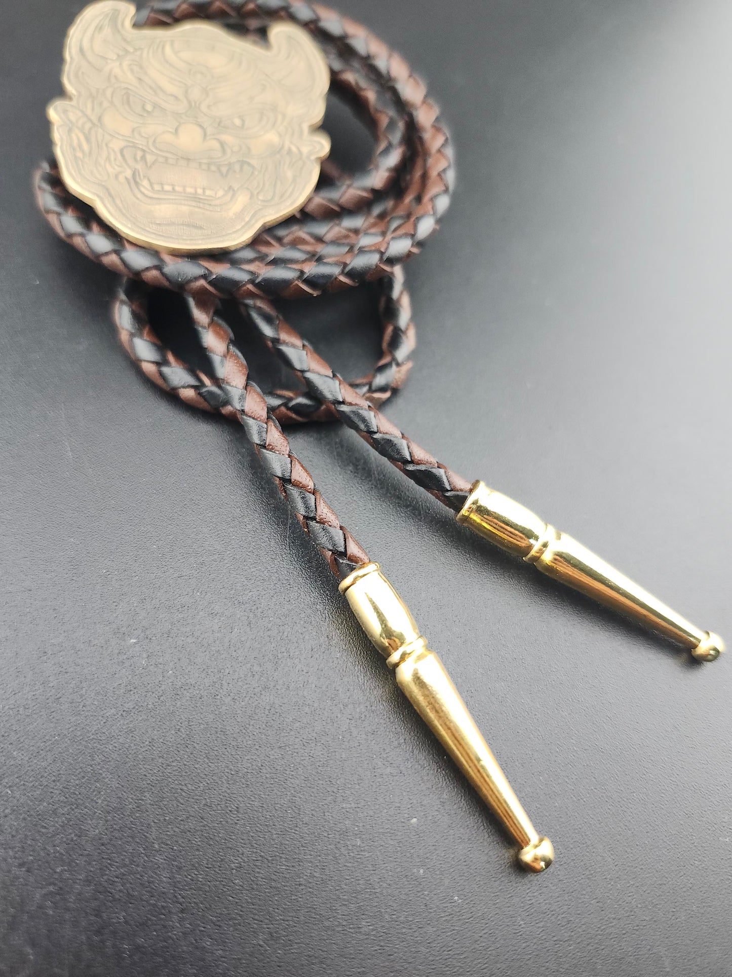 Oni Mask Bolo Tie – Hand-Engraved Brass on Braided Leather