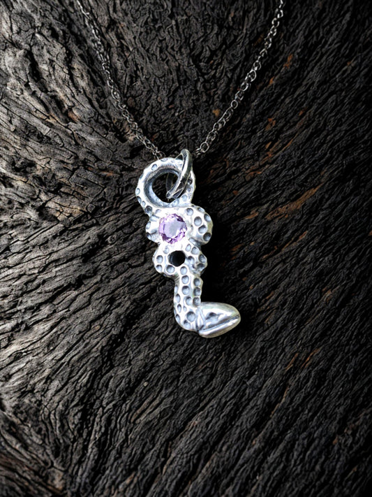 Amethyst’s snake pendant on natural wood grain background, nature, artisan jewelry